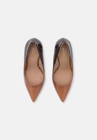 Décolleté a punta con una finitura in vernice lucida marrone chiaro sulla punta e un materiale testurizzato marrone scuro sul retro. Logo dorato all'interno.