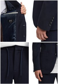 Abito blu navy in tessuto strutturato con taglio slim. Presenta un rever a incavo, polsini con quattro bottoni e coulisse in vita sui pantaloni. Interno foderato con etichetta.