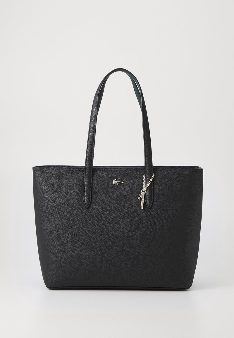 Sac cabas en cuir noir texturé avec deux poignées, logo crocodile argenté et une chaîne argentée avec deux petits charms suspendus à une poignée.