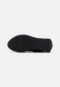 Black athletic shoe sole featuring a textured surface with circular patterns and ridges for grip, designed for optimal traction.