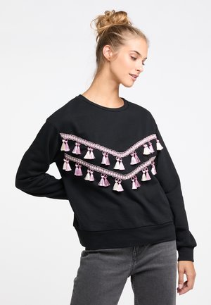 Zwarte sweatshirt met roze en witte franjes langs een decoratieve ketting, voorzien van een klassieke ronde halslijn en een relaxte pasvorm.