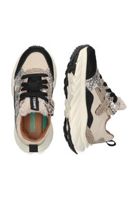 Zapatillas multicolores con una combinación de beige, negro y acentos de purpurina. Parte superior texturizada, cuello acolchado y suela de goma negra gruesa.