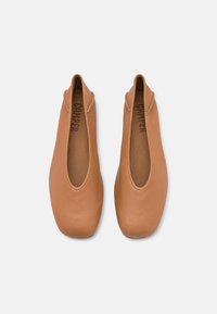 Paire de ballerines en cuir marron clair à enfiler avec des bouts carrés arrondis et des semelles intérieures de marque, vues de dessus sur un fond blanc.