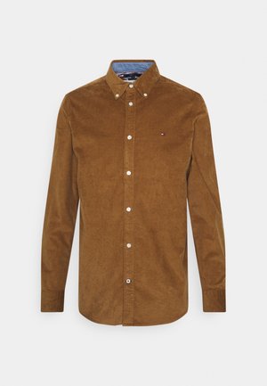 Brown long-sleeve corduroy shirt with button-down collar and white buttons, featuring a small embroidered logo on the chest.