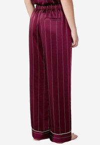 Burgundyfärgade satinpants med vita vertikala ränder, elastisk midja och en enkel bakficka. Fräsch, slät textur. Avslappnad passform.
