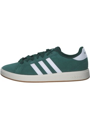 Zielony niski but sportowy Adidas z białymi paskami, białą zakładką na pięcie i beżową podeszwą, widoczny od zewnętrznej strony.