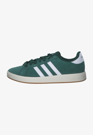 Baskets basses Adidas vertes avec bandes blanches, languette blanche au talon et semelle beige, vues de la partie extérieure.