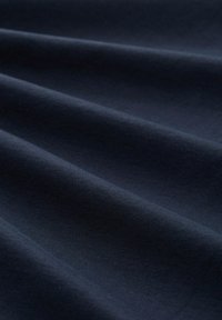 Tela de color navy con una textura suave, que presenta sutiles ondas y pliegues, mostrando un color uniforme y un acabado suave.