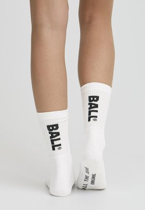 Witte enkelsokken met geribbelde bovenkant, met aan weerszijden vetgedrukte zwarte tekst "BALL" en extra tekst op de zool. Zacht katoenen materiaal.