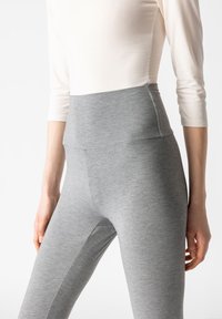 Hochgeschnittene, graue Leggings aus weichem, dehnbarem Material mit einer glatten Textur und minimalen Nähten für Komfort und Flexibilität.