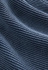 Gros plan sur un tissu tricoté bleu foncé avec un motif côtelé texturé et de doux plis créant des ombres.