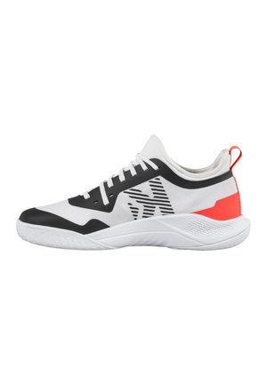 Scarpa sportiva bassa bianca con dettagli neri, tomaia in mesh, lacci, lato con motivo, linguetta rossa sul tallone e suola bianca testurizzata.