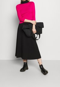 Fuchsia langærmet top, sort A-line nederdel, sort quiltet håndtaske med stropper og sorte ankelsko med kraftige såler.
