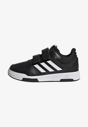 Baskets noires de sport avec une tige en cuir synthétique, deux bandes Velcro, des rayures blanches sur les côtés et une semelle en caoutchouc texturée.