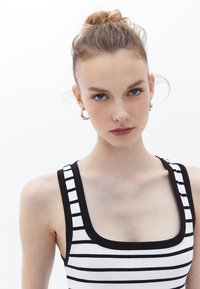 Top a righe bianco e nero con scollo quadrato, realizzato in tessuto a coste, caratterizzato da spalline spesse e un design aderente.