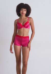 Roze lingerieset met een met kant afgewerkte beha en bijpassende hoge shorts, gemaakt van gladde, glanzende stof.