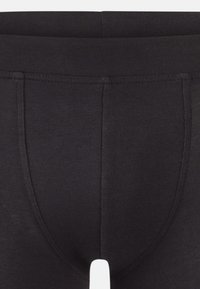 Leggings termici neri realizzati in un tessuto morbido e elasticizzato. Presentano un design aderente con una cintura alta e cuciture rinforzate.