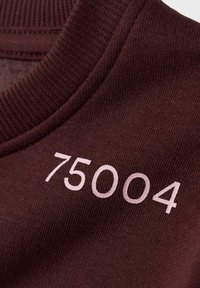 Bordo pleteni materijal s rebrastim izrezom i brojem "75004" izvezenim svijetlorozom, smještenim sa strane.