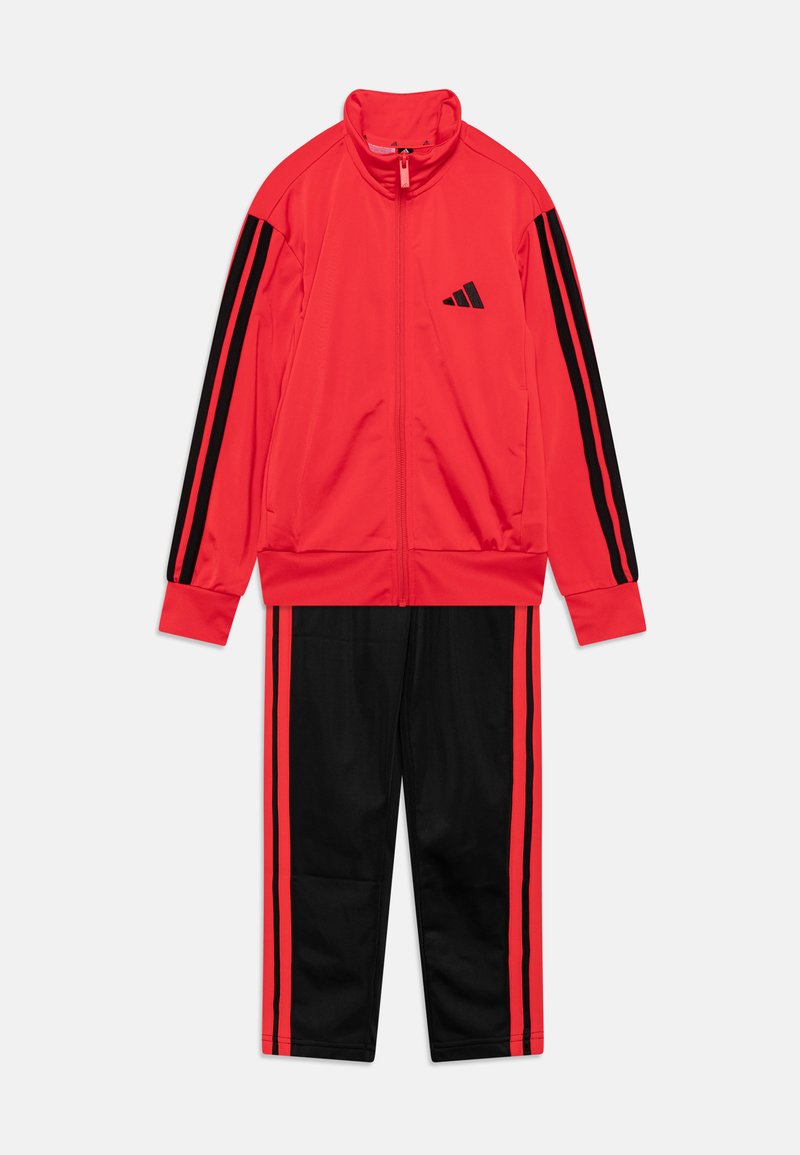 Roter Sportanzug mit schwarzen Akzenten. Die Jacke verfügt über einen hohen Kragen und einen Reißverschluss, während die Hose schwarze Seitenstreifen mit roten Streifen hat.