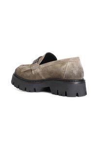 Mocassini in suede taupe con suola in gomma nera spessa. Presentano un tassello decorativo e dettagli metallici sulla parte superiore.