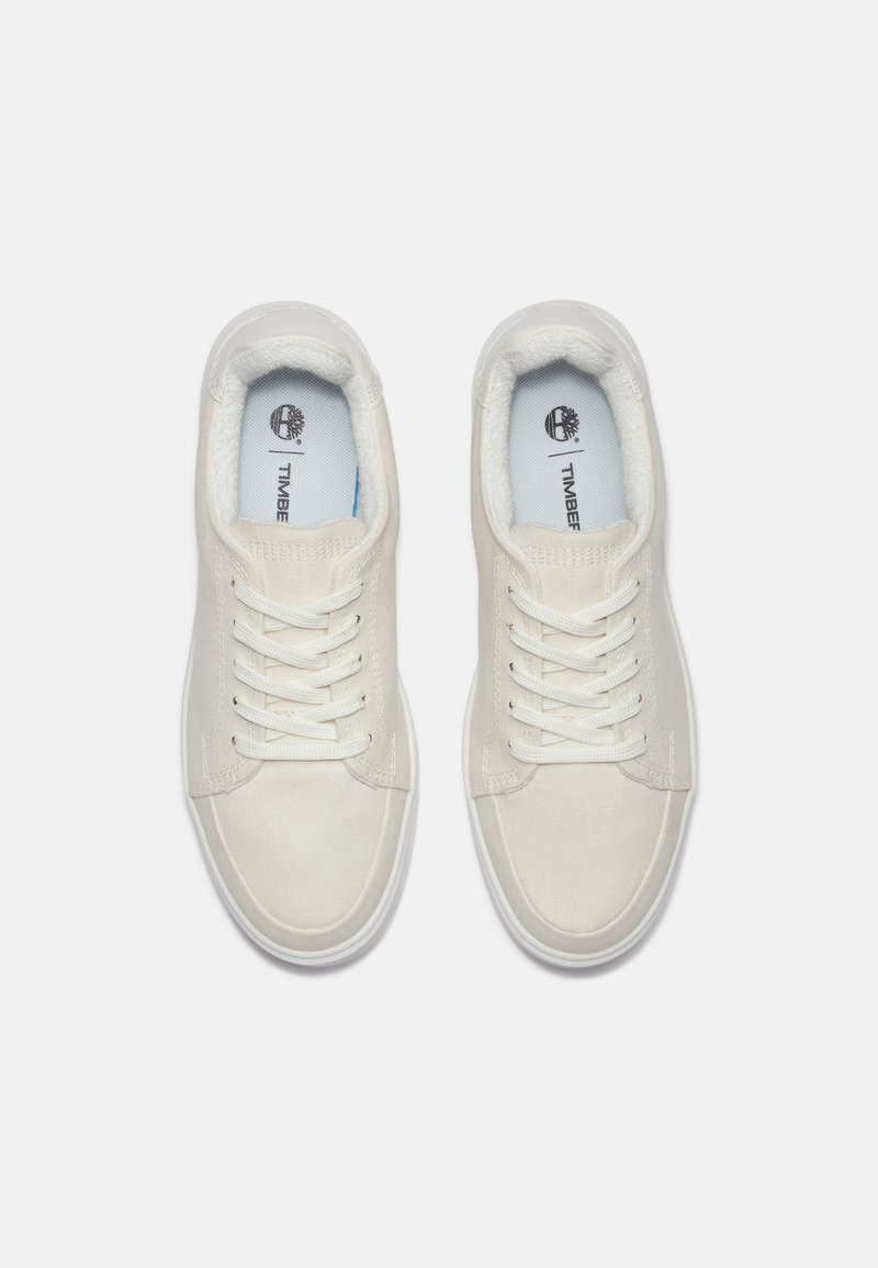 Zapatillas de lona blancas con puntera redonda, cordones planos blancos, collar acolchado y logotipo en la plantilla. Suela de goma para agarre y durabilidad.