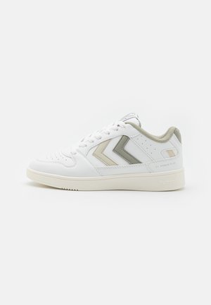 Witte lage sneaker met beige en grijze chevronstrepen, gevoerde kraag, geperforeerde neus en een off-white zool met het opschrift "hummel" en "ST. POWER PLAY."