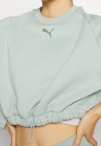 Felpa verde chiaro corta con orlo a coste, caratterizzata da un logo Puma ricamato sul petto e una regolazione con cordino in vita.