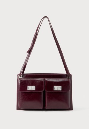 Mørk bordeaux skuldertaske i læder med to frontlommer med klap og sølvfarvede rektangulære låse med drejefunktion. Justerbar rem med sølvknapper.