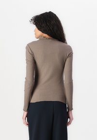 Ribbed brown knit sweater with long sleeves and a scalloped neckline. Features a fitted design and a curved hem at the back.