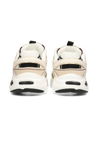 Coppia di scarpe da ginnastica beige e bianche con dettagli neri viste da dietro su sfondo bianco.