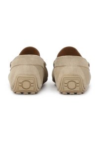 Beige mokasíny z semišu so zaobleným zadočkom. Textúrované podrážky majú kruhové akcenty a malé výčnelky pre lepší grip. Jednoduchý, minimalistický dizajn.