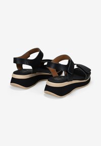 Sandalias de plataforma negras con correas texturizadas, cierres ajustables y suela de crema en contraste. Diseño minimalista con una silueta elegante.