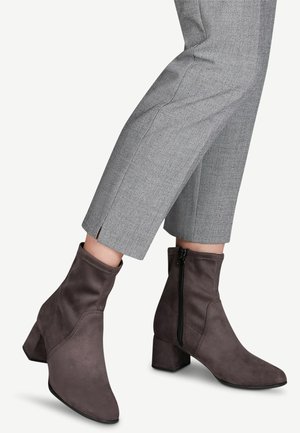 Szare ankle boots z sztucznego zamszu na blokowym obcasie, z bocznym zamkiem błyskawicznym i gładką teksturą, zestawione ze skrojonymi szarymi spodniami.
