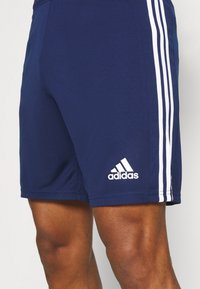 Tumed sportlikud lühikesed püksid, mis on valmistatud siledast kangast, külgedel on kolm valget vertikaalset triipu ning alumisel jalas on valge Adidas'i logo.