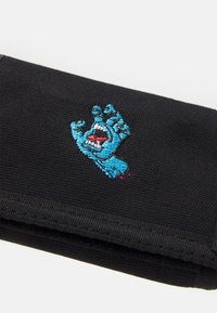Zwarte stoffen portemonnee met een geborduurde blauwe hand met een mond en rode accenten, met een gestructureerd oppervlak en een compact ontwerp.
