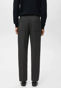 Pantaloni gri din amestec de lână, cu croială dreaptă, două buzunare în spate și textură netedă, asortați cu pantofi negri.