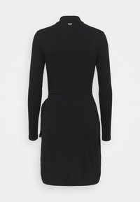 Robe noire en maille côtelée à manches longues avec un col montant et une ceinture nouée à la taille, vue de dos sur fond blanc.