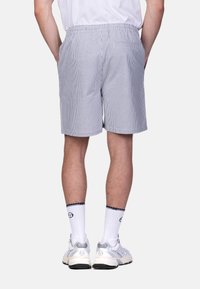 Blaue und weiße gestreifte Shorts mit einem elastischen Bund, seitlichen Taschen und einer Gesäßtasche. Aus leichtem Stoff, knielange Schnittform.