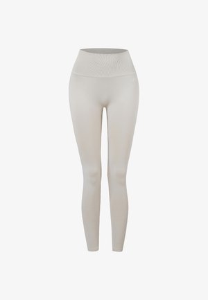 Beigenväriset korkeavyötäröiset saumattomat leggingsit, joissa leveä ribbivyötärö ja kapea istuvuus nilkkoihin asti.