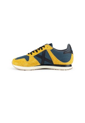 Zapatilla baja con ante amarillo y paneles de malla azul, cordones y ribete negros, y suela blanca.