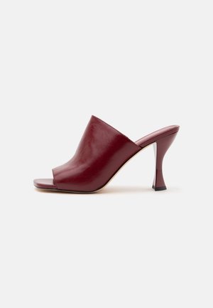 Single burgundy leather high heel mule with an open toe and curved mid-height heel on a white background.