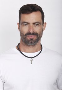 Sort flettet læderhalskæde med en sølv ankh vedhæng, båret over en simpel hvid t-shirt. Glat tekstur; minimalistisk design.