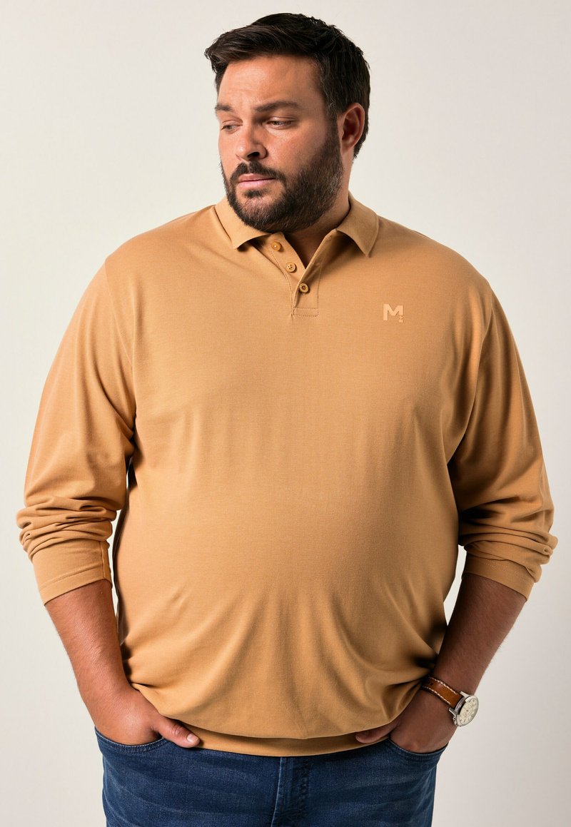 Polo-paita vaaleasta kahvinsävyisestä kankaasta, pitkät hihat, kolmonen napitus kauluksessa, huomaamaton logo rinnassa, yhdistetty tummansinisiin farkkuihin.