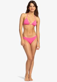 Růžový bikini set s trojúhelníkovým topem a nízkými kalhotkami, s tenkými ramínky a hladkým textilním povrchem.