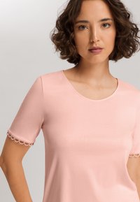 Rosa kortärmad t-shirt med rundad halsringning, med en scalloped kant vid ärmsluten. Mjuk, slät tyg med en figurnära design.