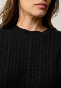 Czarny wełniany sweter z prążkowaną fakturą i okrągłym dekoltem. Materiał wydaje się miękki i ciepły.