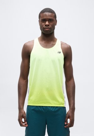 Homme athlétique portant un débardeur de sport jaune fluo et un short bleu foncé, debout face à l'avant sur un fond uni.