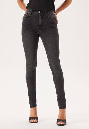 Jeans skinny neri a vita alta in denim, caratterizzati da una texture liscia, un design aderente e tasche frontali con dettagli di cucitura discreti.