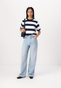 Striped navy and white short-sleeve t-shirt, light blue wide-leg jeans, black handbag, and black flats. Smooth fabric and relaxed fit.