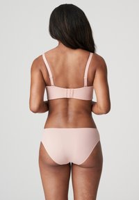 Vaaleanpunainen bikinitsetti, jossa on yksinkertainen bralette, jossa on säädettävät hihnat ja koukkukiinnitys, yhdistettynä vastaaviin matalavyötäröisiin alushousuihin.